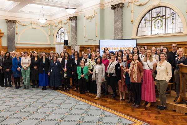 A large group of people stand together and pose and smile at the dress for success event.